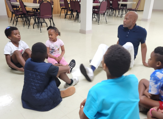 a few scholars sit in circle with pastor 